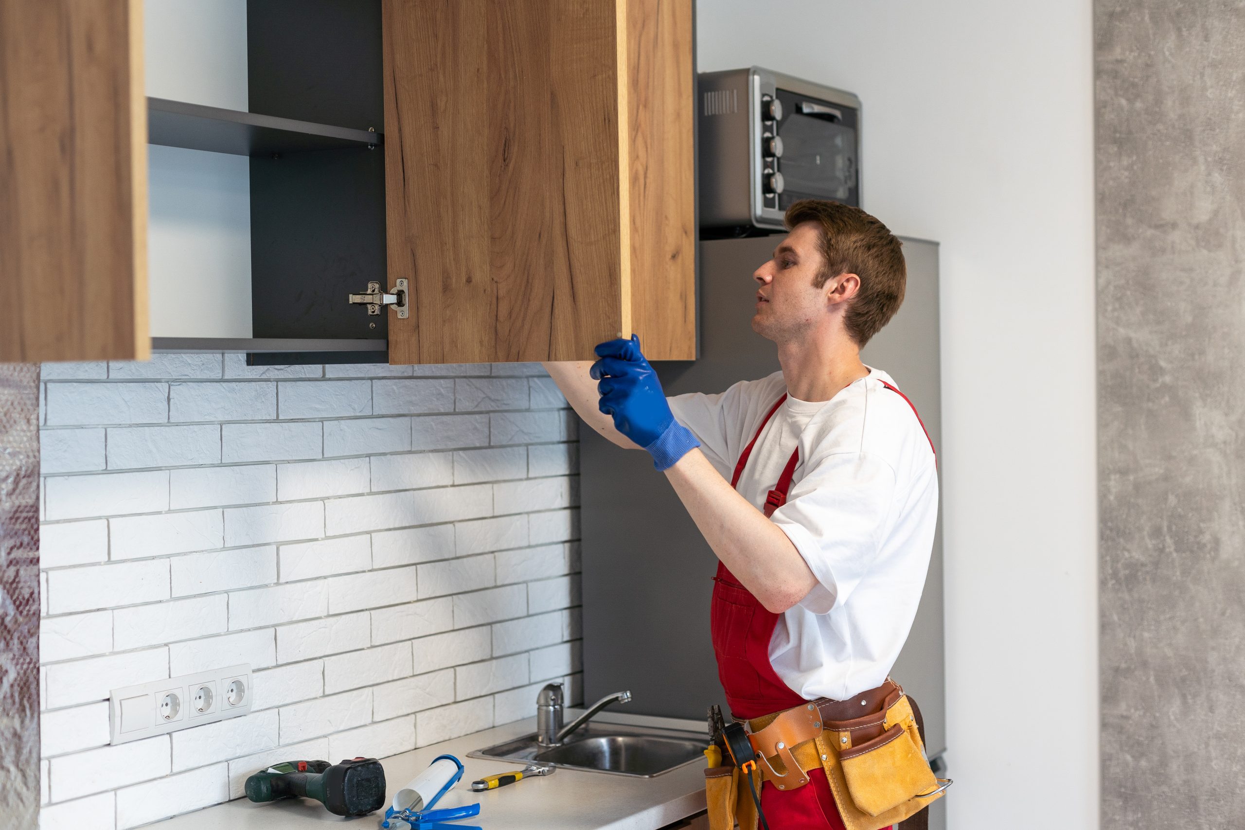 Worker installing new cabinets in a modern kitchen.
