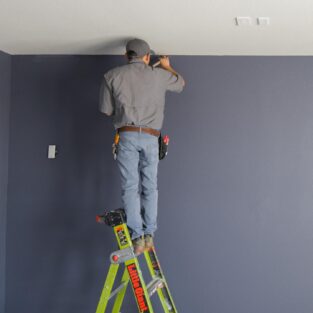 Handyman Painting top of a wall