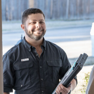 Friendly handyman shaking hands with a customer at the front door.