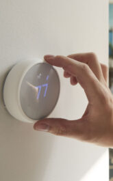 Close Up Of Male Hand Adjusting Digital Central Heating Thermostat In Home