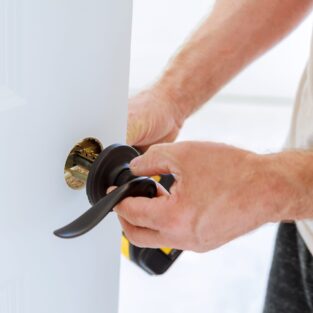 Install the door handle with a lock, Carpenter tighten the screw, using an electric drill screwdriver, close-up.