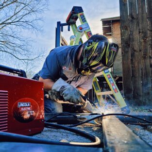 Handyman welding a sliding gate in the driveway of a house